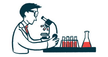 A scientist looks through a microscope in a laboratory, alongside a rack of vials and a beaker filled with blood.