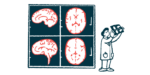 A clinician holds up an imaging scan next to four giant images of the human brain shown on a wall.
