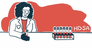 A researcher holds a vial of blood while looking at a rack of filled vials.