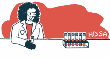 A researcher holds a vial of blood while looking at a rack of filled vials.