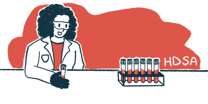 A researcher holds a vial of blood while looking at a rack of filled vials.